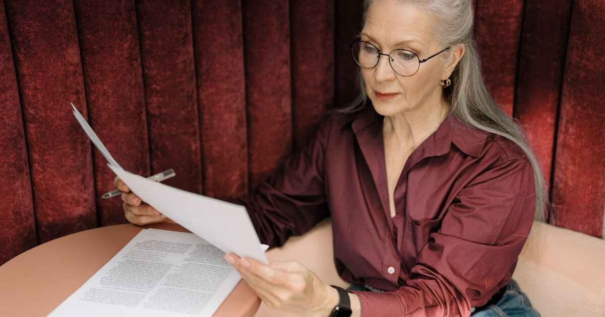 Women Reading Paper and Focusing On Cost of Living Payment