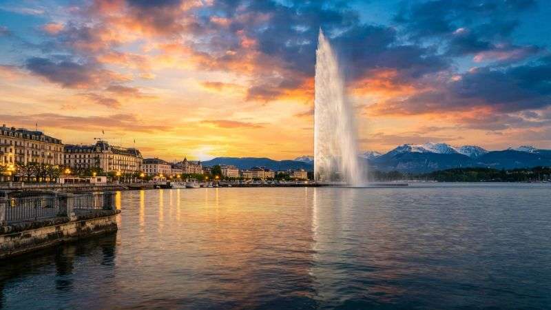 Jet d'Eau fountain on Lake Geneva during golden sunset.