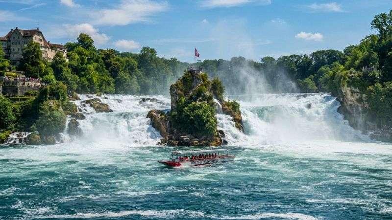 Sightseeing boat approaching the powerful Rhine Falls in Switzerland.